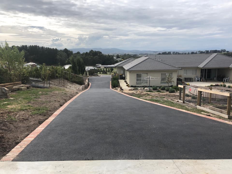 looking down a long brick edged asphalt driveway