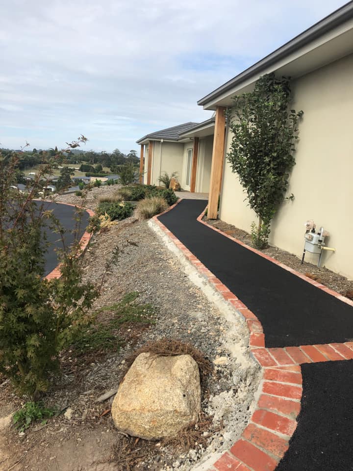 looking across the top tier of an asphalt path running alonside a tuscan style house